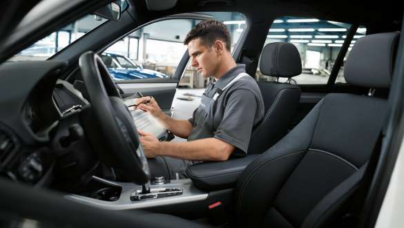 Vediamo un meccanico seduto all'interno di una BMW intento ad una riparazione
